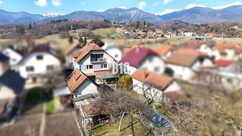 Ein Einfamilienhaus in Turany mit einem Schuppen, einem Garten und den umliegenden Bergen im Hintergrund.