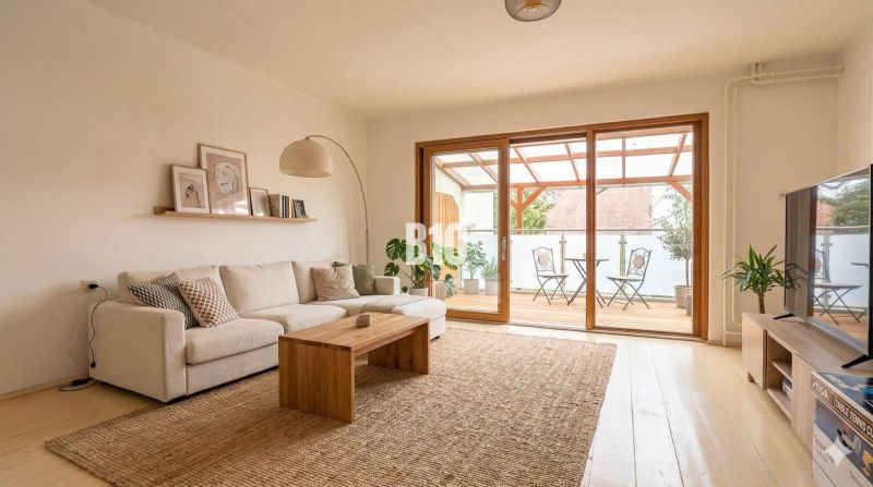 Wohnzimmer in einem Einfamilienhaus mit bequemer Couch, Holztisch und Terrasse.