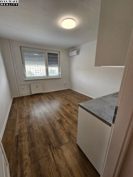 Ein Studio-Apartment mit Holzdekorboden, Klimaanlage und einem großen Fenster für Licht.