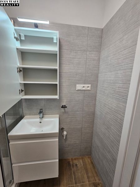 Badezimmer in einem Studio-Apartment mit Waschbecken und Bodenbelag in Holzoptik.