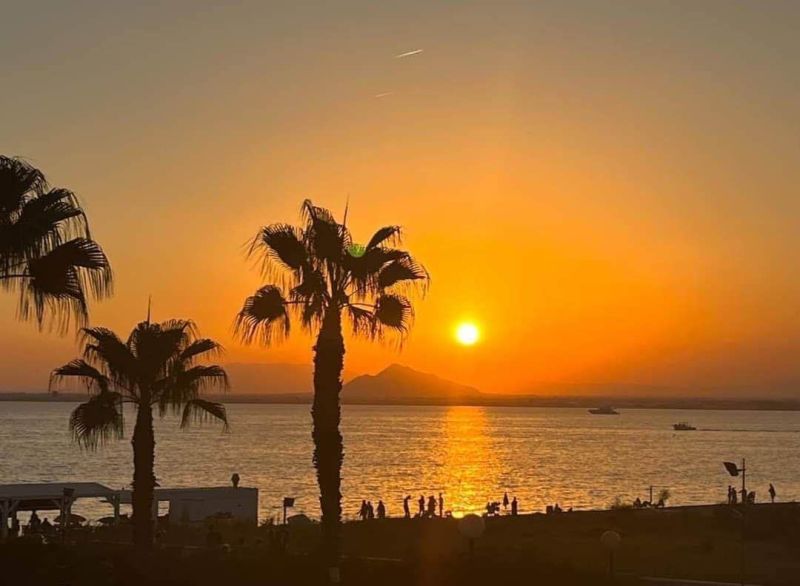 Sonnenuntergang mit Palmen und Meer in La Manga del Mar Menor, Spanien.