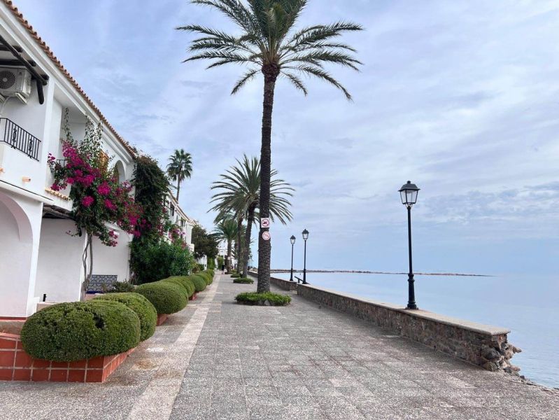Die Strandpromenade in La Manga del Mar Menor, Spanien, gesäumt von Palmen und Lampen.