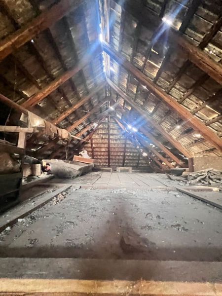 Dachboden in einem Einfamilienhaus mit Holzbalken und natürlicher Beleuchtung.
