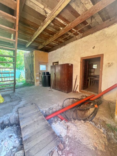 Das Innere eines Einfamilienhauses mit Holzbalkendecke, aufgerissenem Boden und einer Leiter.