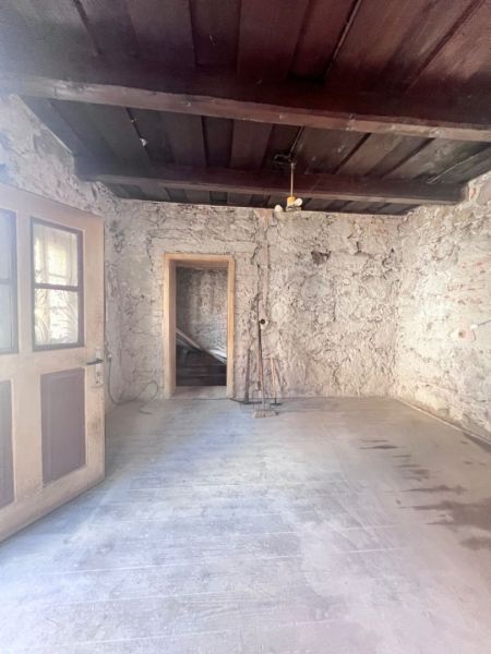 Rustikaler Raum in einem Einfamilienhaus mit Steinwänden und einem Boden in Holzoptik.