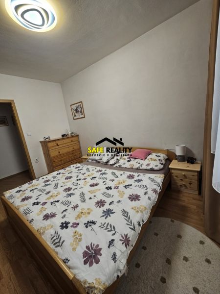 Schlafzimmer in einer 3-Zimmer-Wohnung mit Bett, Kommode und Boden in Holzoptik.