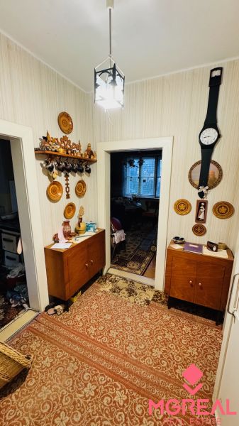 Ein Flur in einer 3-Zimmer-Wohnung mit Möbeln, Teppich und Holzelementen an den Wänden.