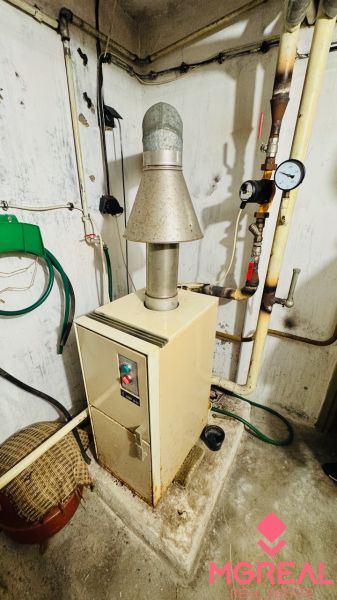 Heizung im Technikraum einer 3-Zimmer-Wohnung mit Leitungen und Rohren an den Wänden.