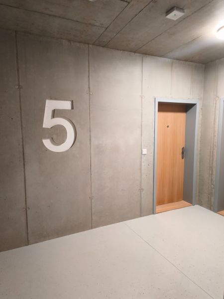 Betonwand mit der Nummer fünf und Holztüren in einer Zweizimmerwohnung.