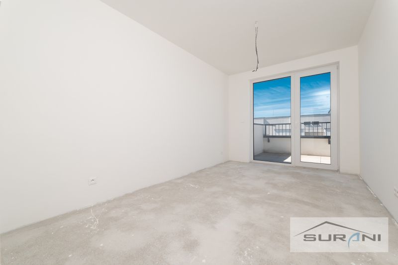 Ein leeres Zimmer in einer 3-Zimmer-Wohnung mit Zugang zum Balkon und unfertigem Boden.