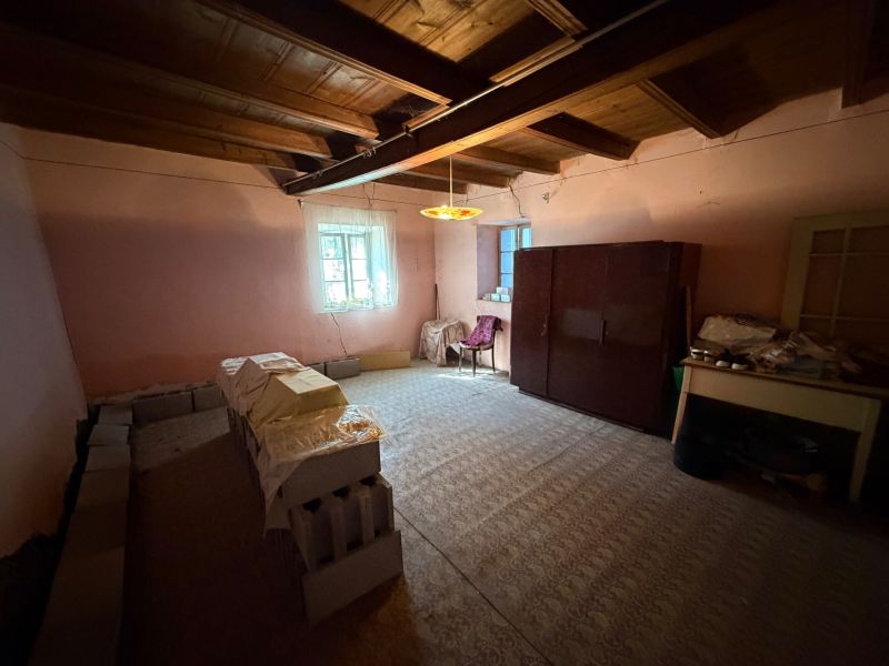 Ein Zimmer in einem Einfamilienhaus mit Möbeln, Ziegelstapeln und einer Holzdecke.