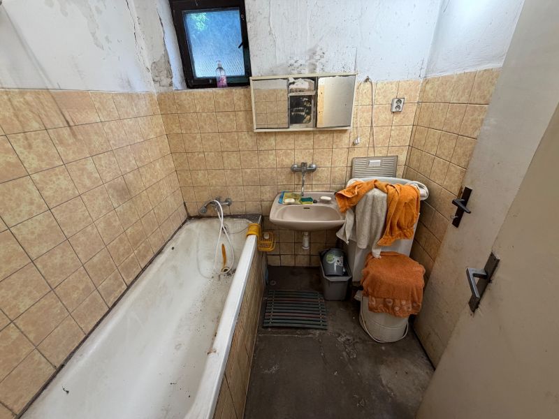 Ein Badezimmer in einem Einfamilienhaus mit einer Badewanne, einem Waschbecken und beigefarbenen Fliesen an den Wänden.