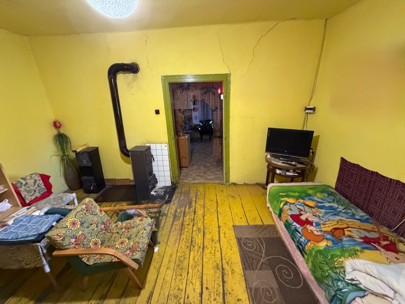 Ein Zimmer in einem Einfamilienhaus mit einem Ofen, gelben Wänden und einem Boden in Holzoptik.