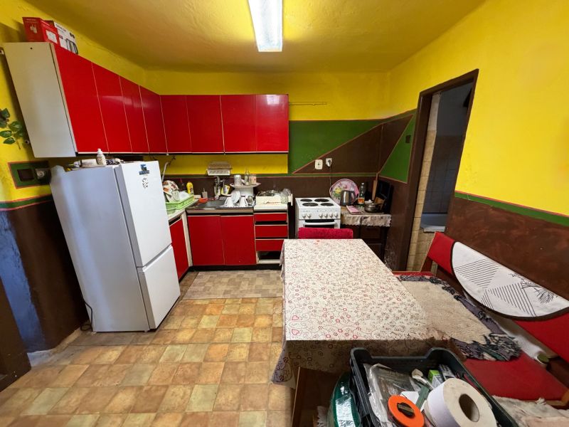 Einfamilienhaus mit Küche, roten Schränken und weißen Geräten.