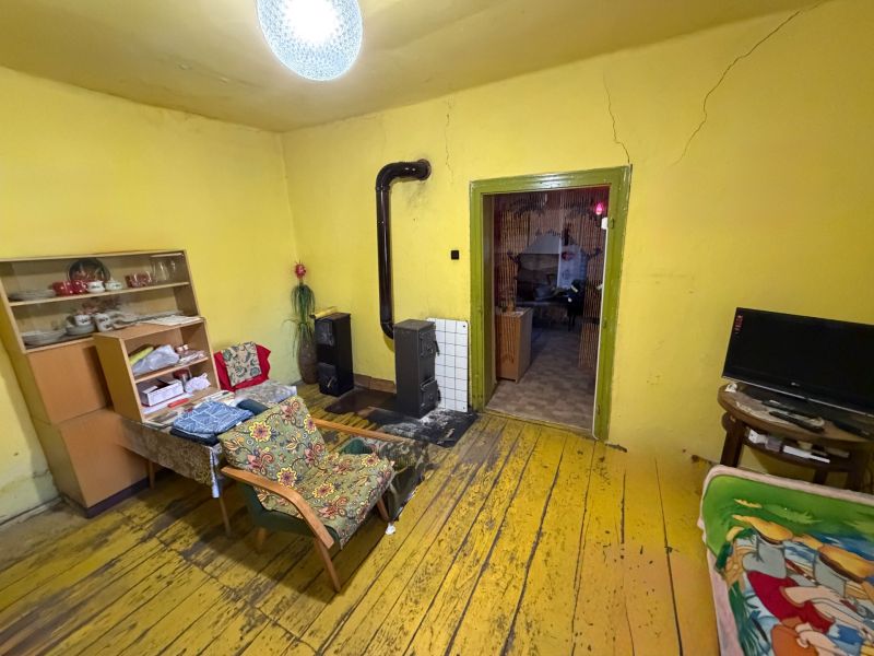 Wohnzimmer in einem Einfamilienhaus mit Ofen, gelben Wänden und einem Boden mit Holzdekor.