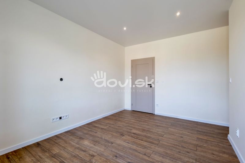 Ein leerer Raum mit einem Holzboden und hellen Wänden in einem Einfamilienhaus.