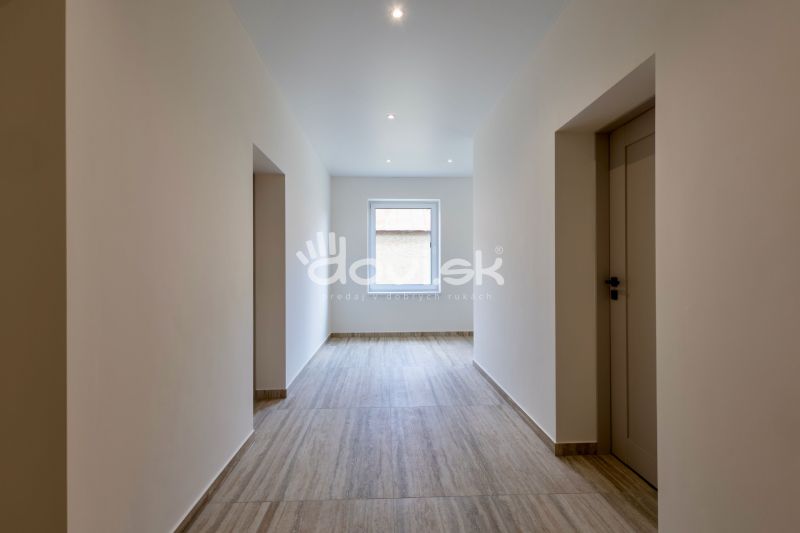 Ein Flur in einem Einfamilienhaus mit einem Boden in Holzoptik und einem Fenster am Ende.
