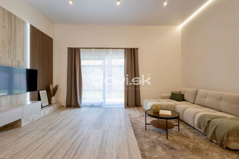 Wohnzimmer eines Einfamilienhauses mit Sofa, Holzboden und Fernseher an der Wand.