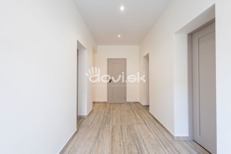Ein Flur in einem Einfamilienhaus mit einem Boden in Holzoptik und weißen Wänden.