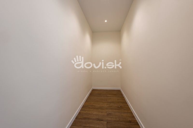 Ein enger Flur in einem Einfamilienhaus mit weißen Wänden und einem Boden in Holzoptik.