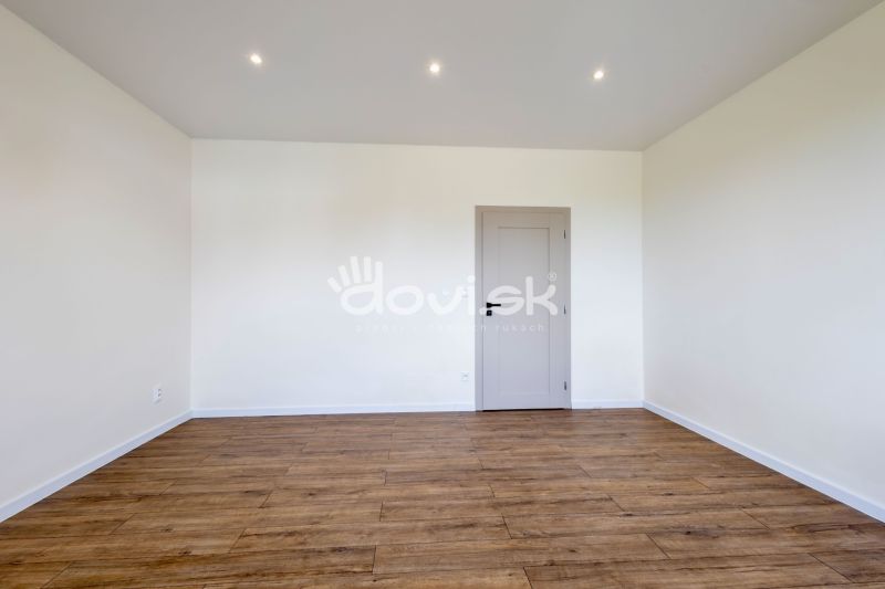 Ein Raum mit einem Holzboden und weißen Wänden in einem Einfamilienhaus.