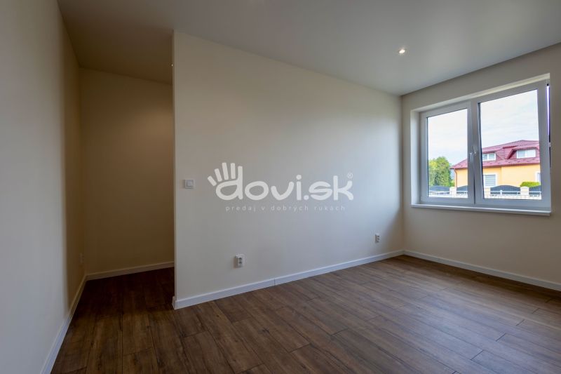 Ein Zimmer in einem Einfamilienhaus mit einem Holzboden und einem großen Fenster.