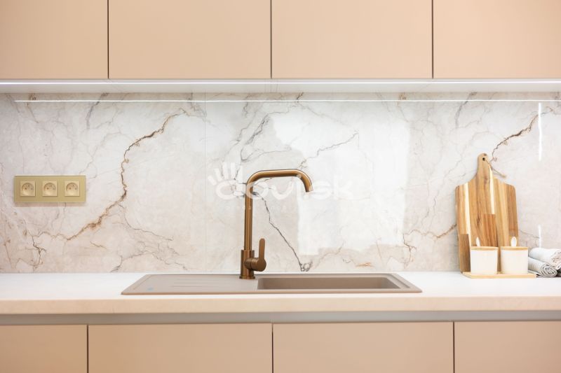 Küchenzeile mit goldenem Wasserhahn und Marmorverkleidung in einem Einfamilienhaus.