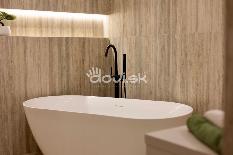 Freistehende Badewanne mit modernem schwarzen Wasserhahn in einem Einfamilienhaus.