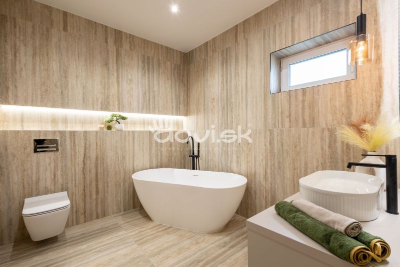 Badezimmer in einem Einfamilienhaus mit Holzboden, Badewanne und dekorativer Beleuchtung.