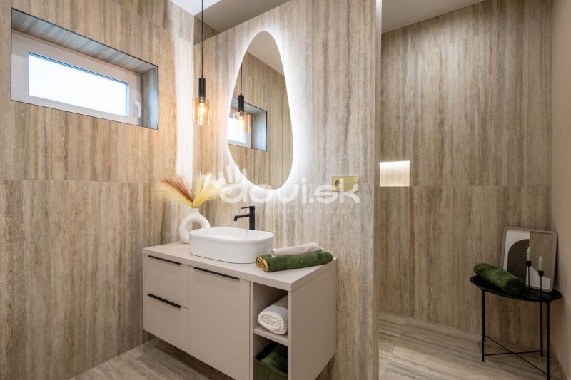 Badezimmer mit ovalem Spiegel und natürlichen Tönen, Boden mit Holzdekor.