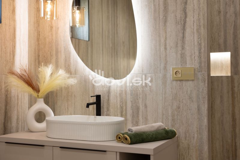 Ein Badezimmer in einem Einfamilienhaus mit einem ovalen Spiegel, einem Waschbecken und Lichtern.