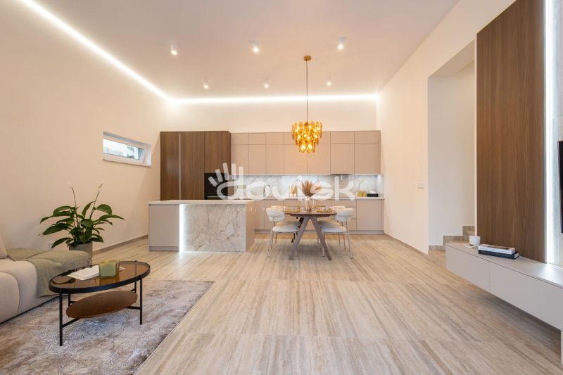 Küche und Wohnzimmer in einem Einfamilienhaus mit dekorativer Leuchte und Boden mit Holzdekor.