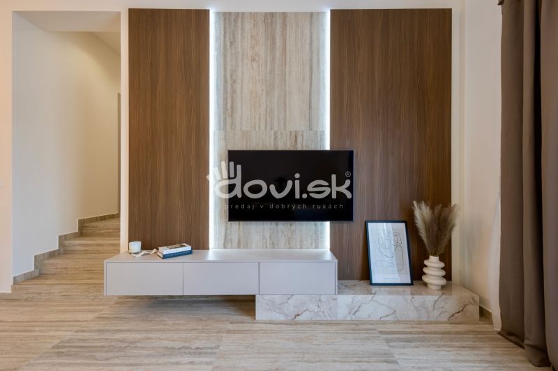 Innenraum eines Einfamilienhauses mit einer Wand in Holzoptik, einem Fernseher und Dekorationen.