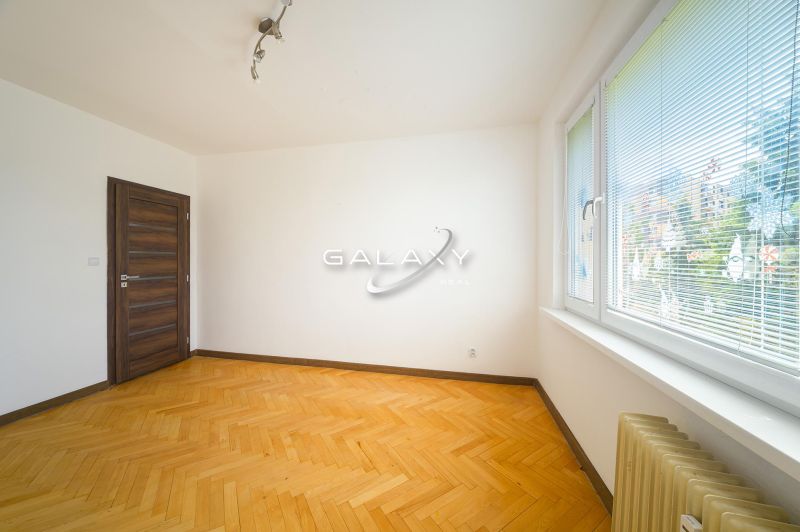 Ein Zimmer in einer 3-Zimmer-Wohnung mit einem Boden in Holzoptik und großen Fenstern.