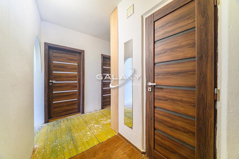 Der Flur in der 3-Zimmer-Wohnung mit Holztüren und einem Boden mit Holzdekor.
