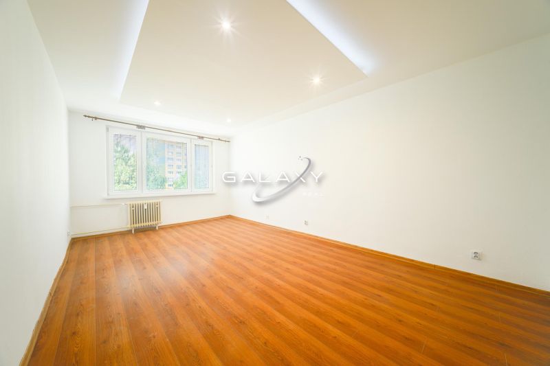 Geräumiges Wohnzimmer mit Holzboden in einer 3-Zimmer-Wohnung, weiße Wände.