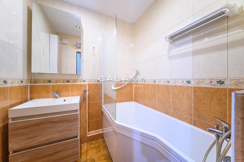 Badezimmer mit Badewanne und Waschbecken in einer 3-Zimmer-Wohnung mit Fliesen und Spiegel.