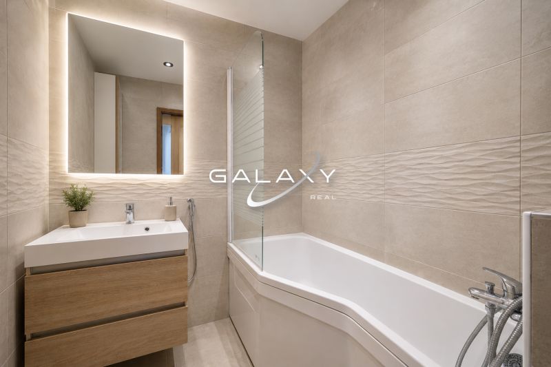 Badezimmer in einer 3-Zimmer-Wohnung mit Badewanne, Waschbecken und Boden mit Holzdekor.