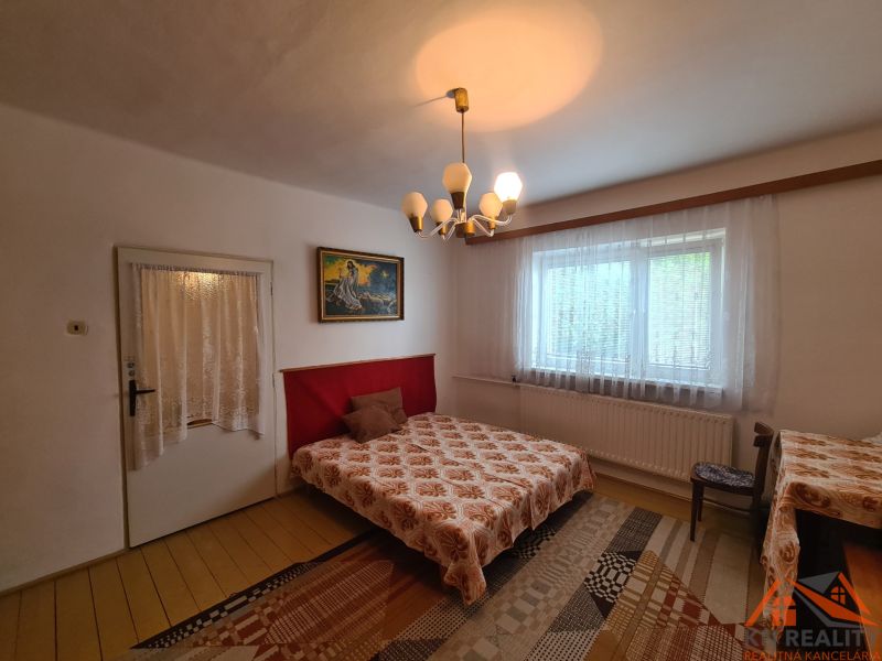 Schlafzimmer im Einfamilienhaus mit dekorativem Kronleuchter, Vorhängen und Teppich.