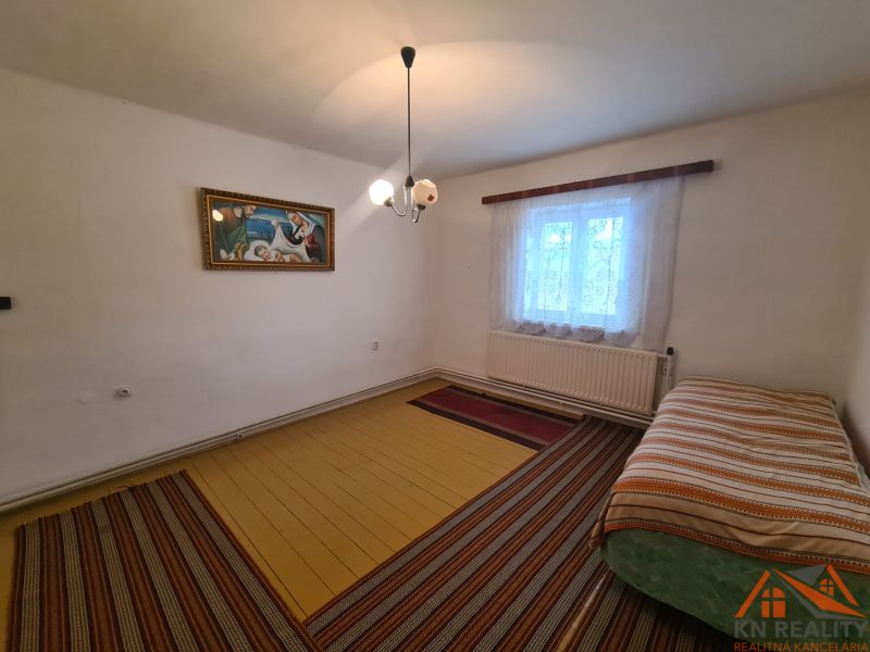 Innenraum eines Einfamilienhauses mit Bett, Bild und Fenster mit Vorhängen.