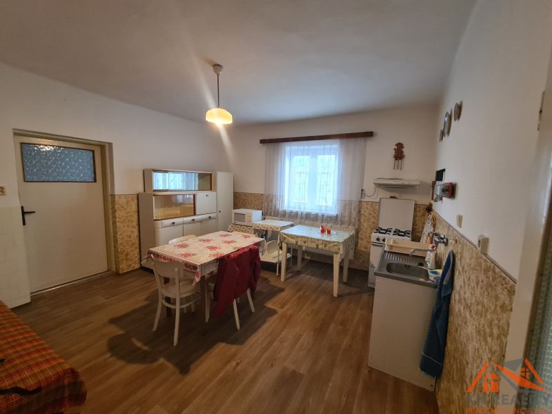 Eine Küche in einem Einfamilienhaus mit einem Boden in Holzoptik, einfache Möbel und ein Esstisch.