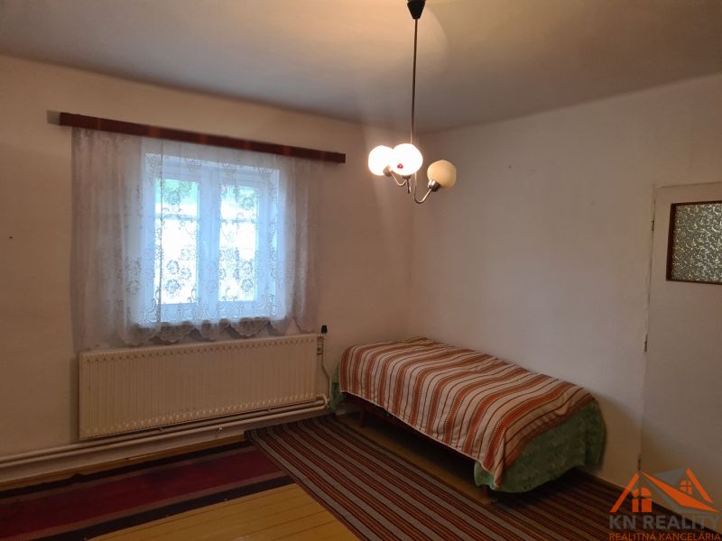 Einfaches Zimmer mit Bett und Fenster, Einfamilienhaus, Teppich und Vorhänge.