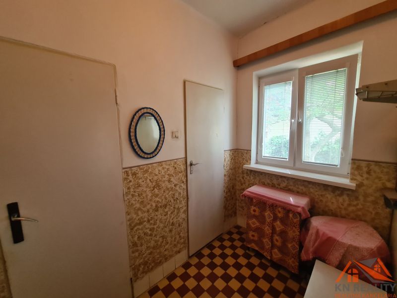 Ein Innenraum in einem Einfamilienhaus mit gefliestem Boden und einem Fenster mit Jalousien.