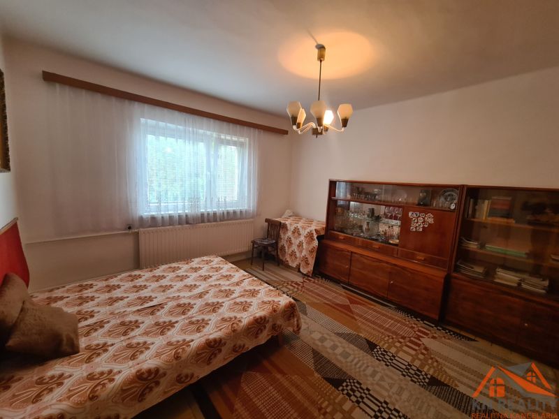 Ein Zimmer mit ausziehbarem Sofa, älterer Vitrine und Vorhang, in einem Einfamilienhaus.
