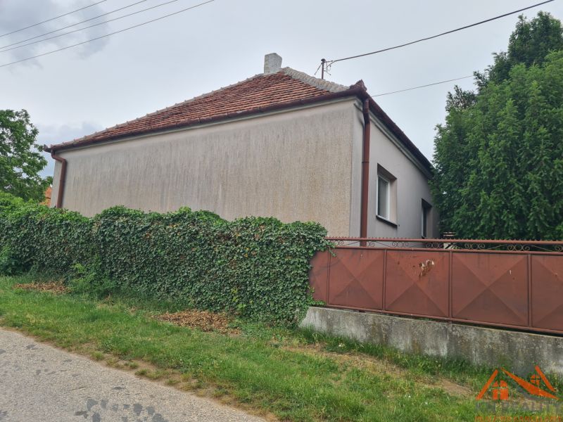 Ein Einfamilienhaus in Dulovce mit einem von Grün umwachsenen Zaun, das an der Straße liegt.