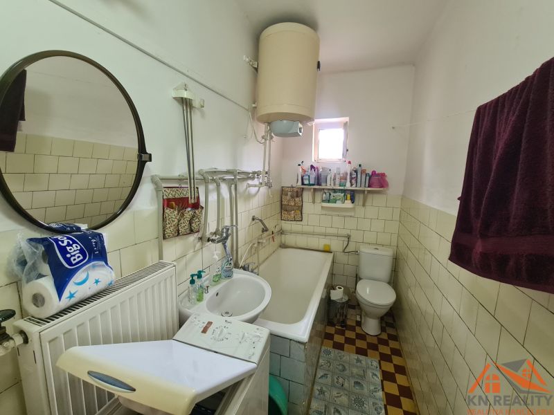 Badezimmer mit Spiegel, Waschbecken, Badewanne und Waschmaschine in einem Einfamilienhaus.