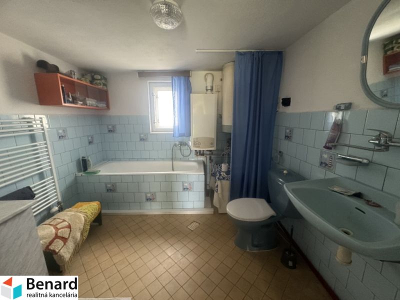 Ein Badezimmer in einem Einfamilienhaus mit blauen Fliesen und einer Badewanne.