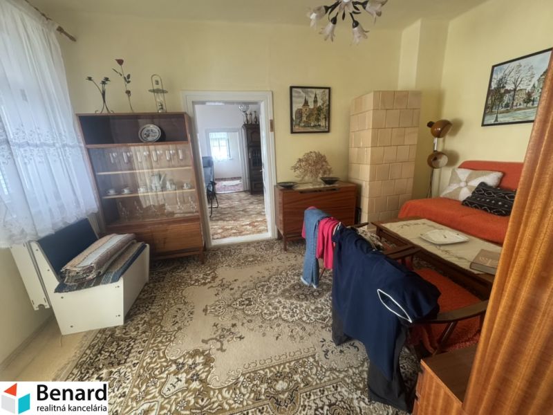 Ein Zimmer in einem Einfamilienhaus mit einer Sitzgarnitur, einer Vitrine und einer Zimmerpflanze.