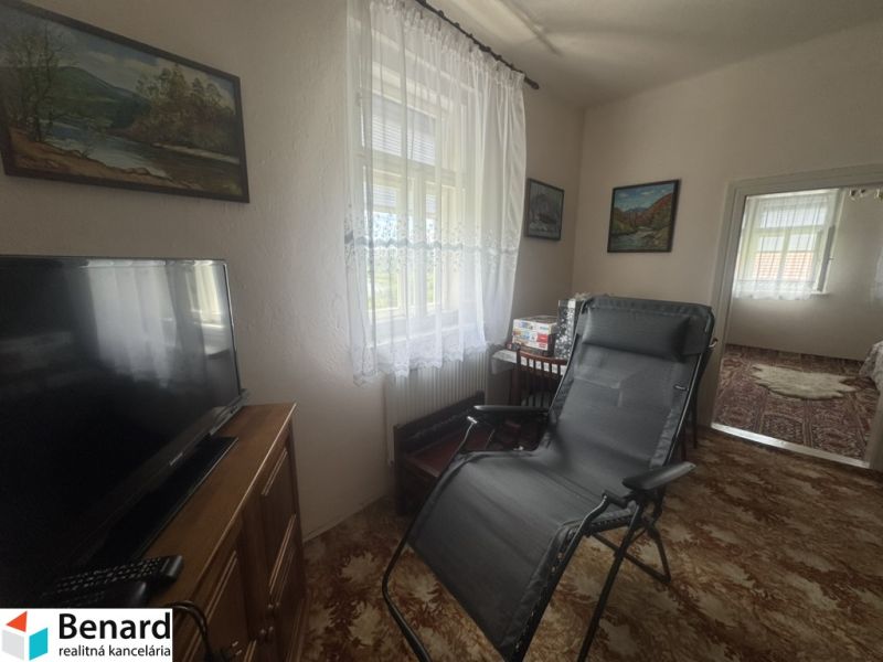 Wohnzimmer in einem Einfamilienhaus mit Fernseher, Sessel und Wanddekorationen.