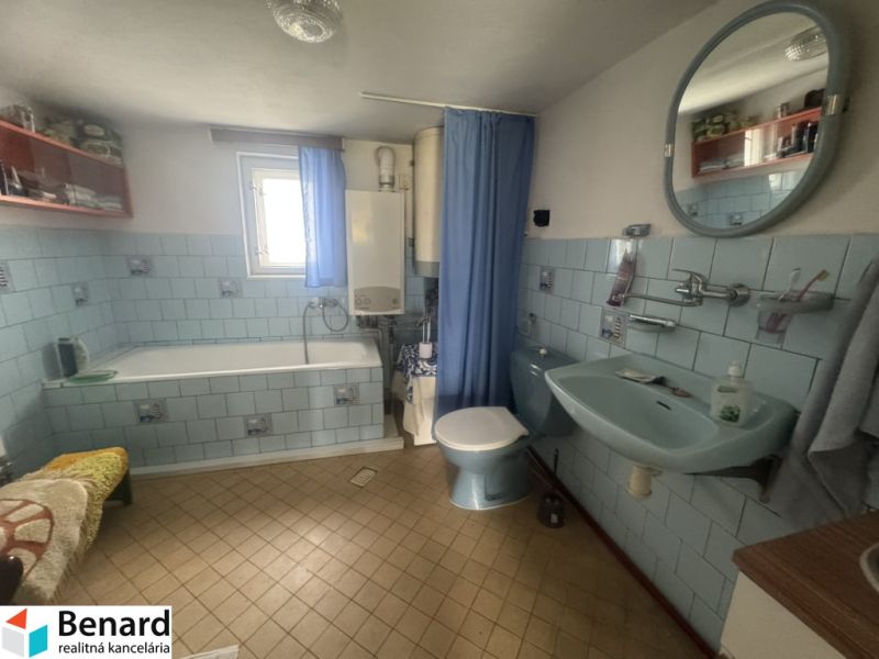 Ein Badezimmer in einem Einfamilienhaus mit blauen Fliesen und einer Badewanne.